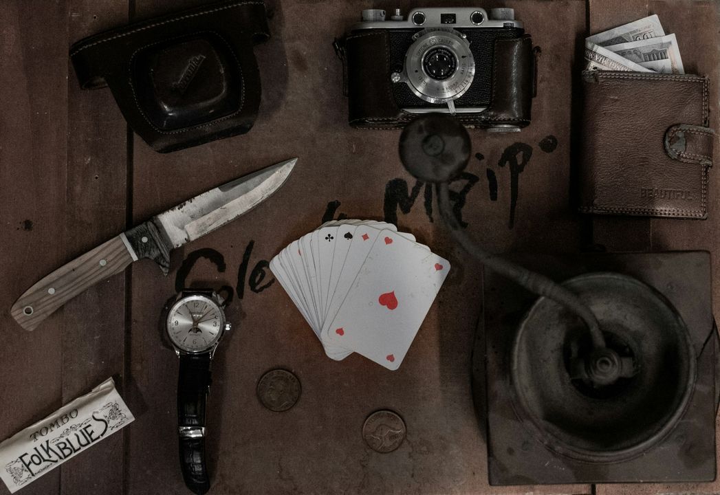 Предметы, создающие атмосферу детектива или триллера: старая камера, нож, карты, деньги.