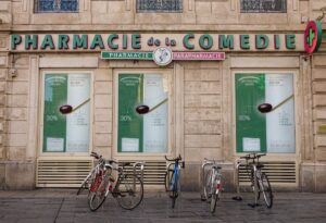 Фасад французской аптеки "Pharmacie de la Comédie" с велосипедами у входа — идеальная атмосфера для уютного киновечера с французскими комедиями, которые поднимут настроение.